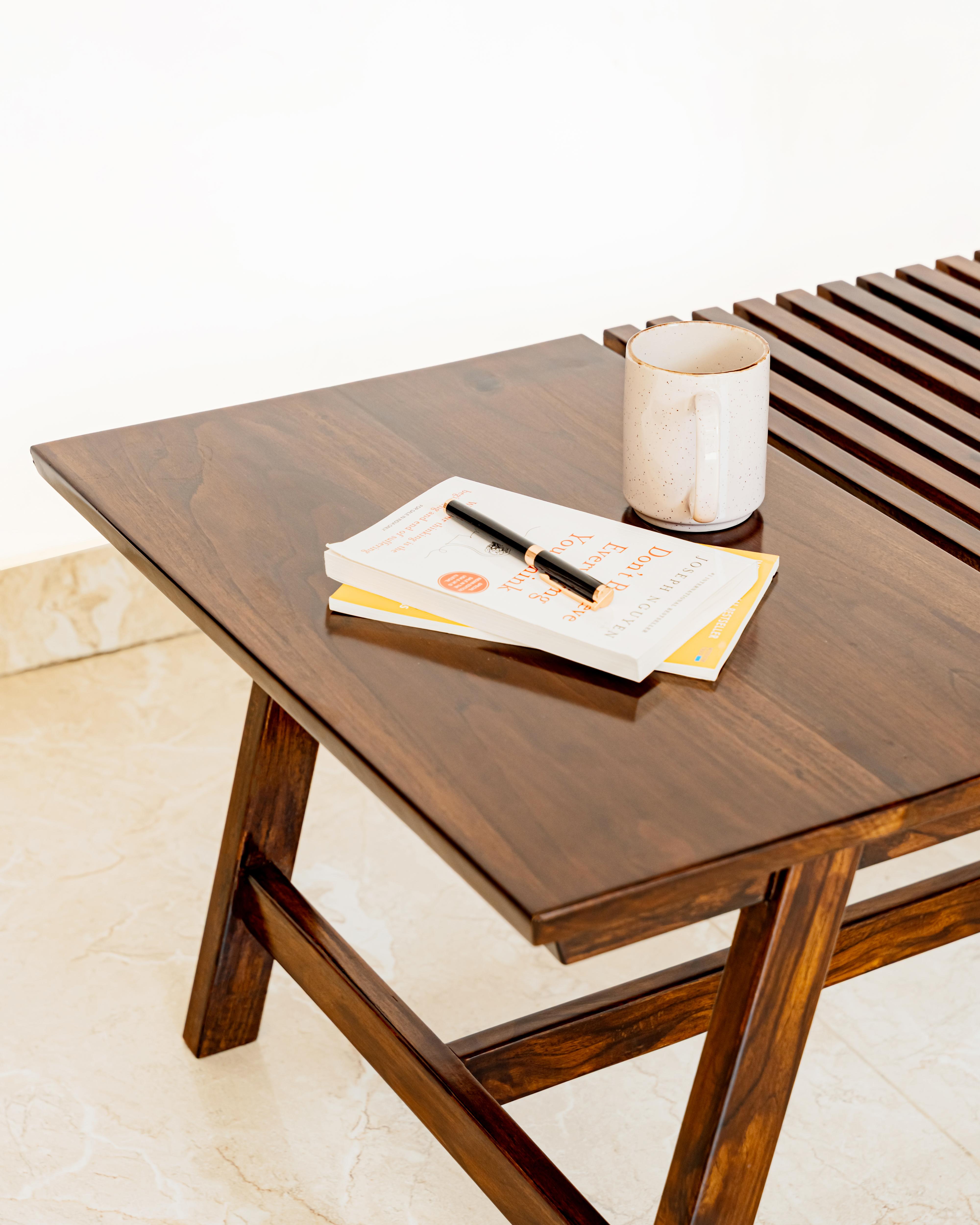 Wooden coffee table with a mug, notebook, and pen on it 