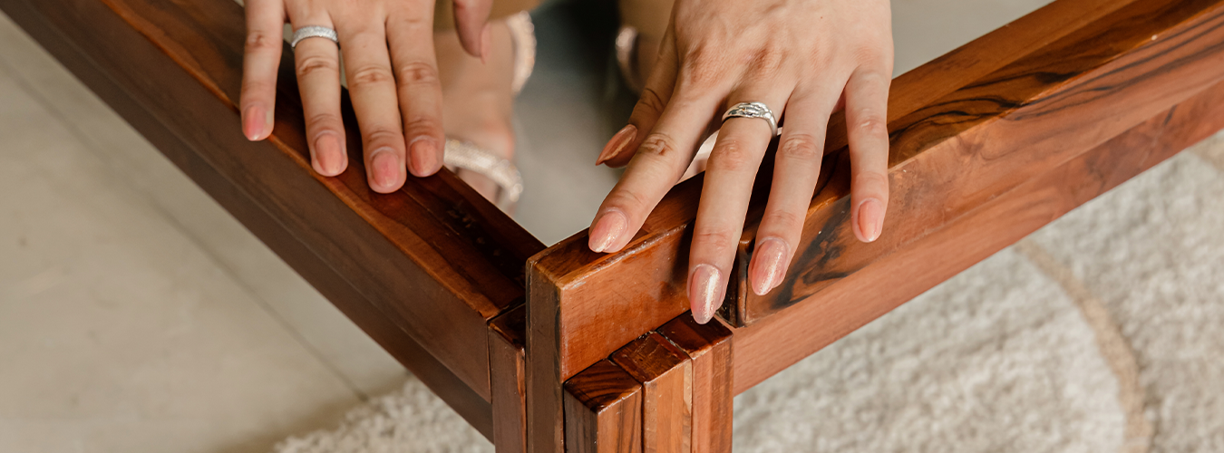 Close-up of hands adjusting a wooden bed frame 