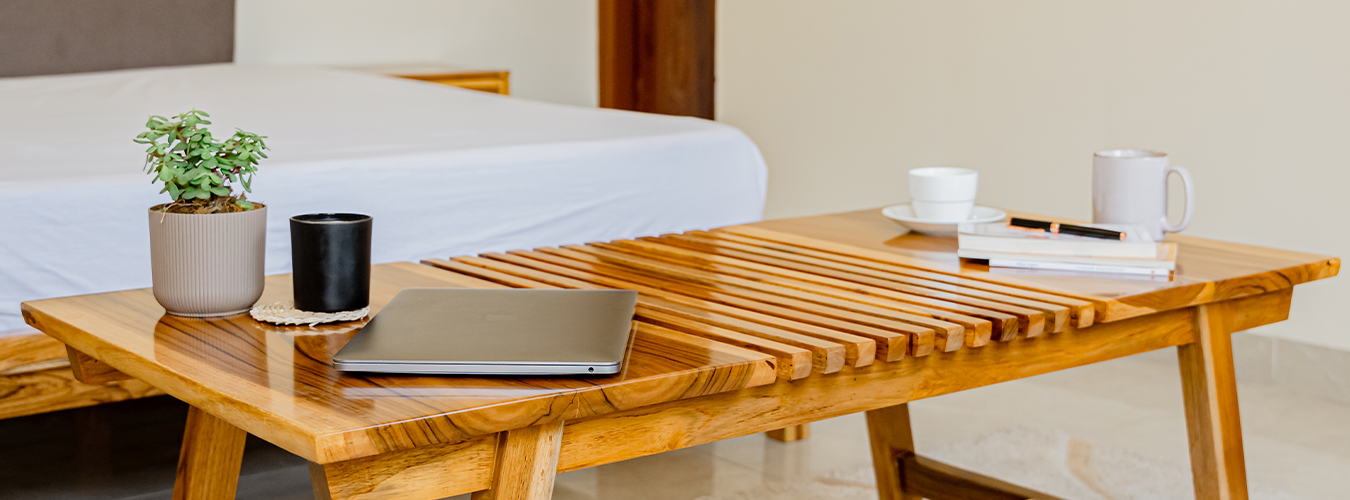 Wooden coffee table with laptop, mug, and plant in a living room setting